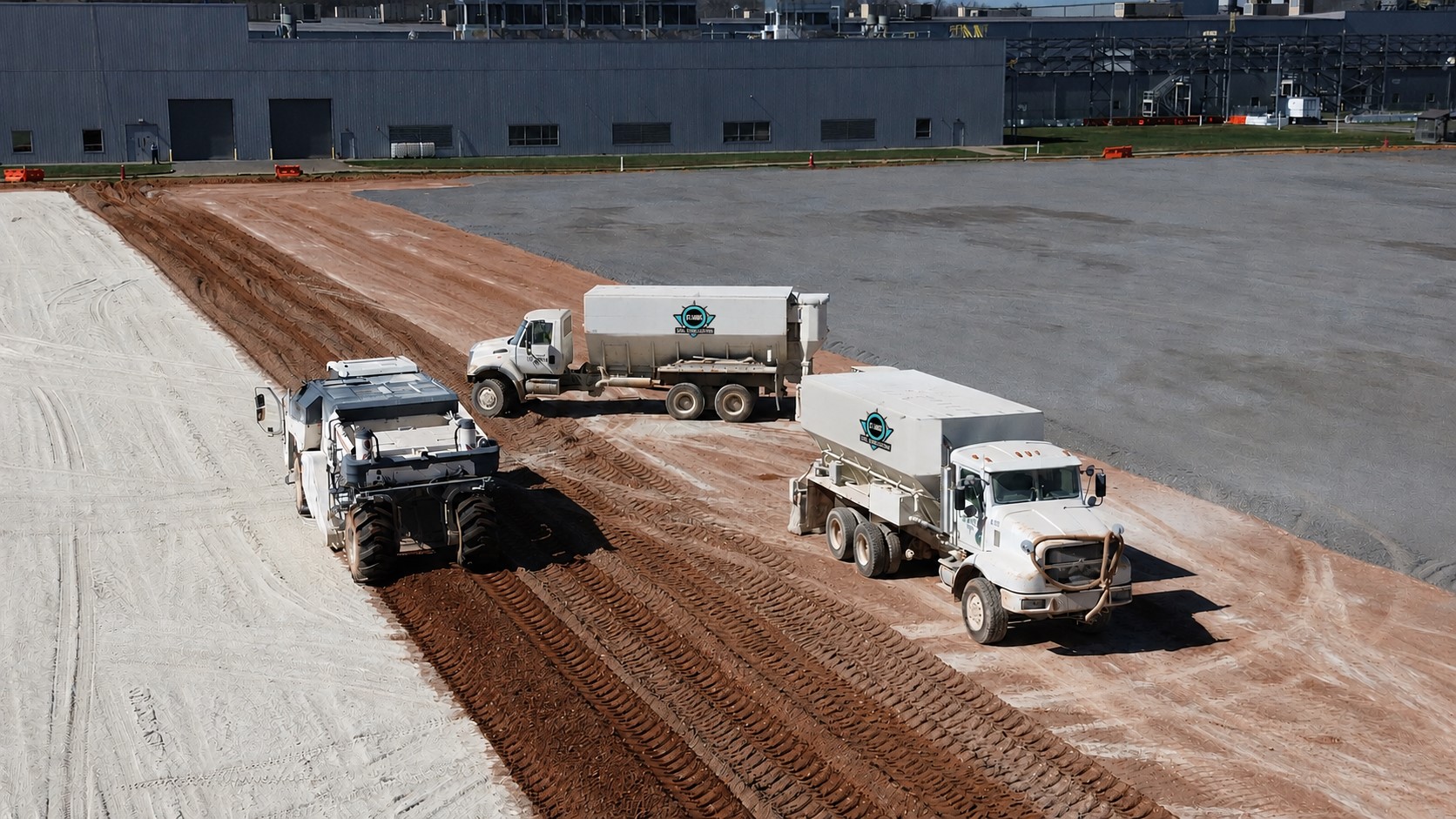 Soil stabilization spreader trucks and reclaimer working an industrial building pad